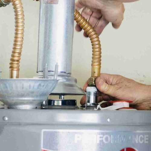 Adult male making adjustments and tightening connections on new hot water heater