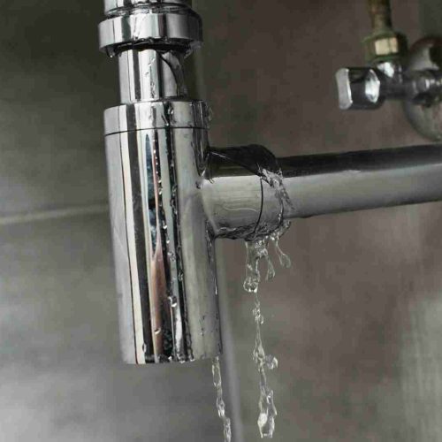 Damaged pipe with leaking water on grey background